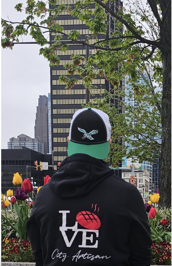 Man wearing a Love City Artisan hoodie looking at Center City skyline